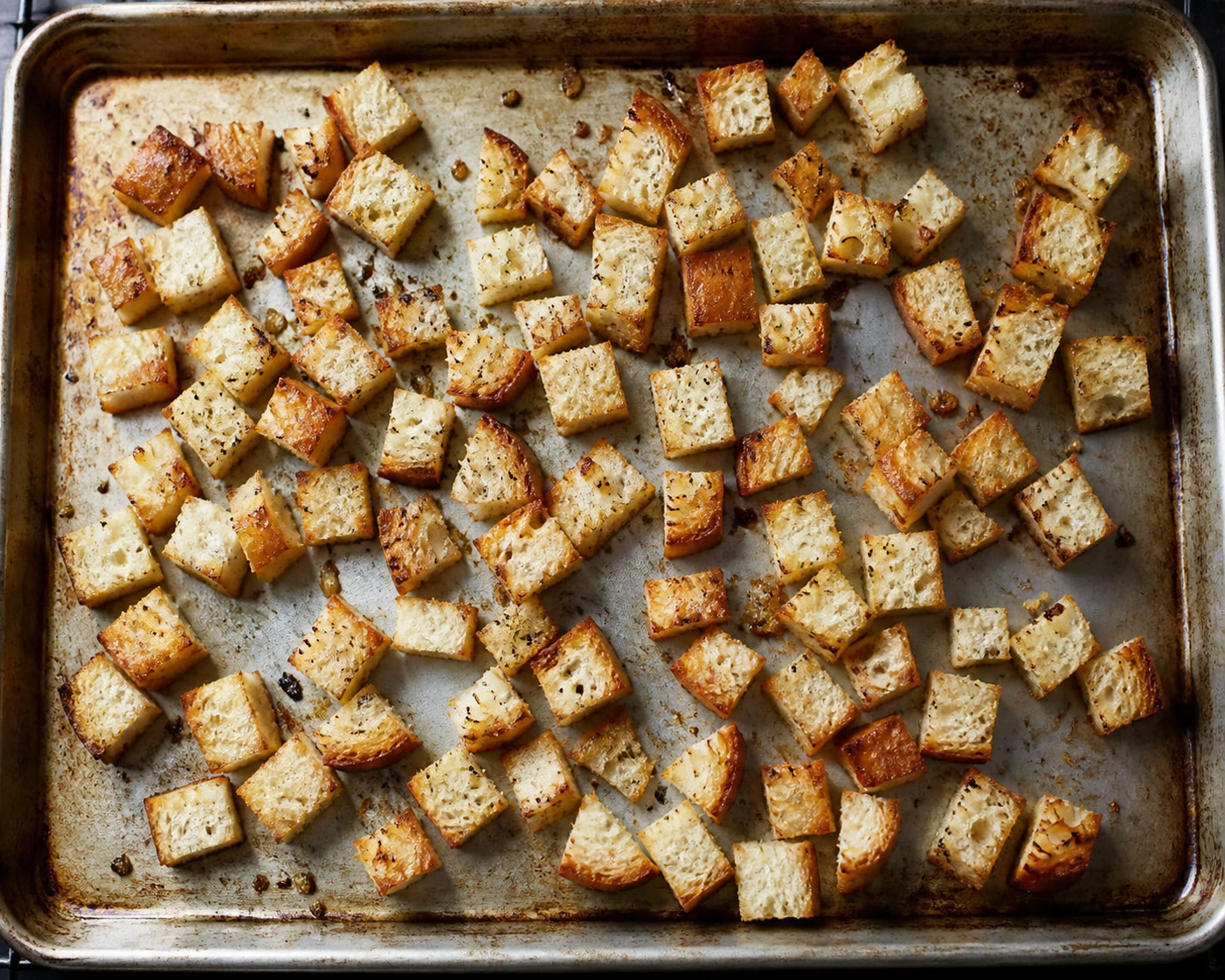 Bacon-fat seasoned sourdough cubes bake on a sheet pan to become crunchy salad croutons.