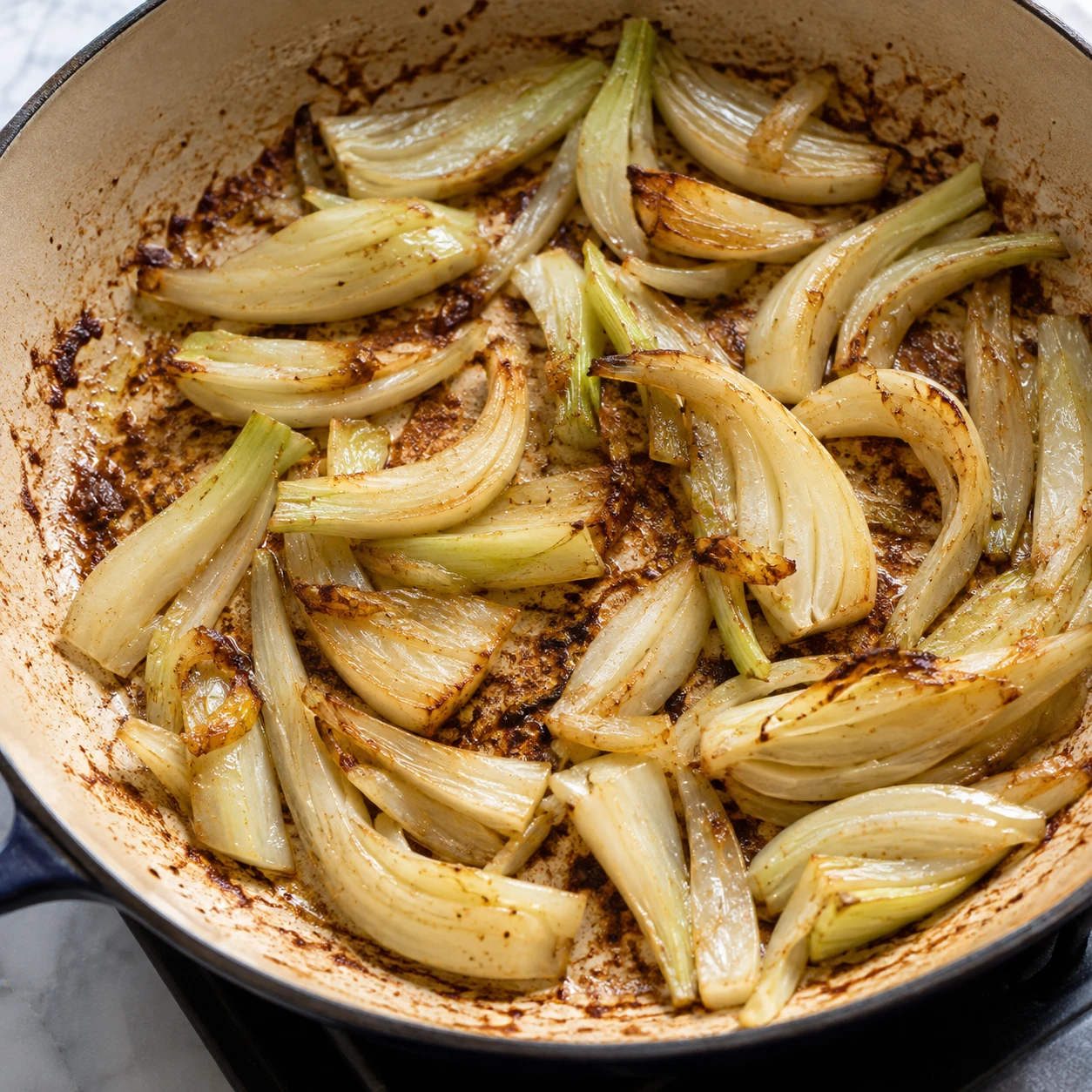 Sliced fennel softens in a skillet with browned chicken fond ready to become pan sauce.