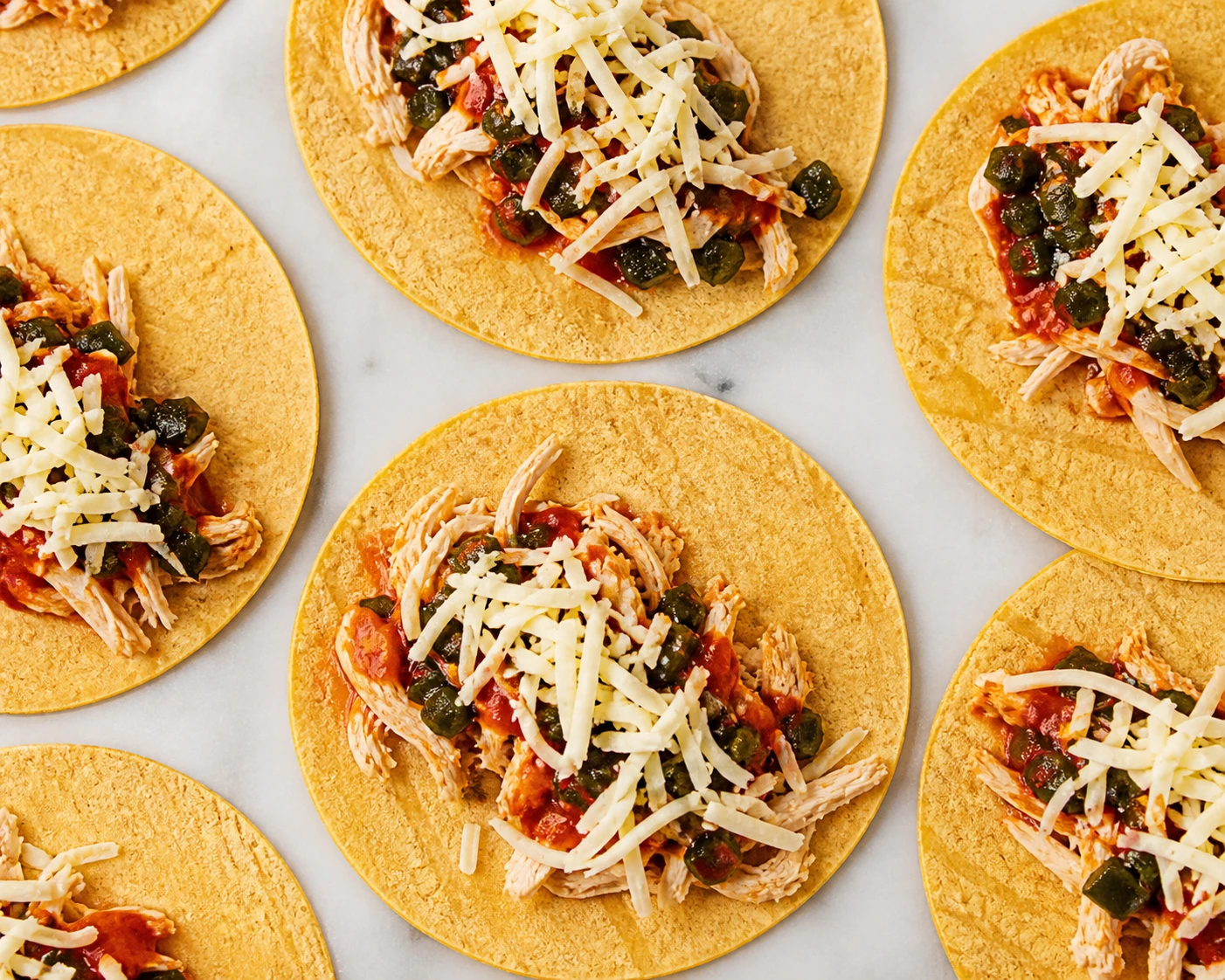 Warm corn tortillas hold chicken, roasted poblano peppers, red sauce, and cheese before being rolled.