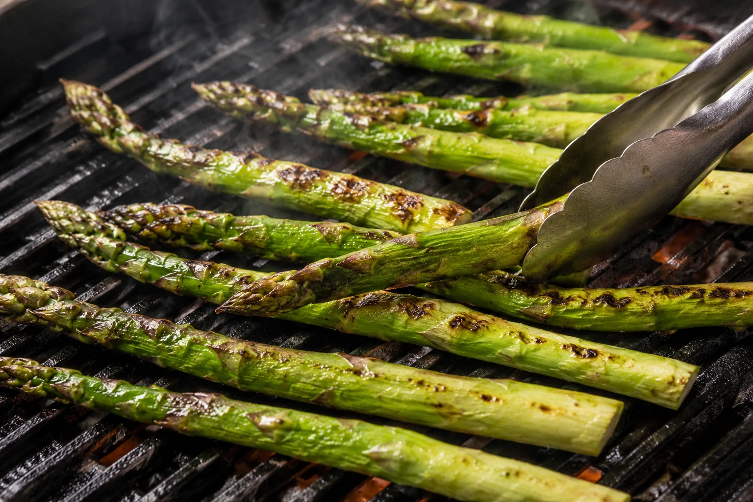 Asparagus spears show early char marks on a hot grill while their centers remain bright green.