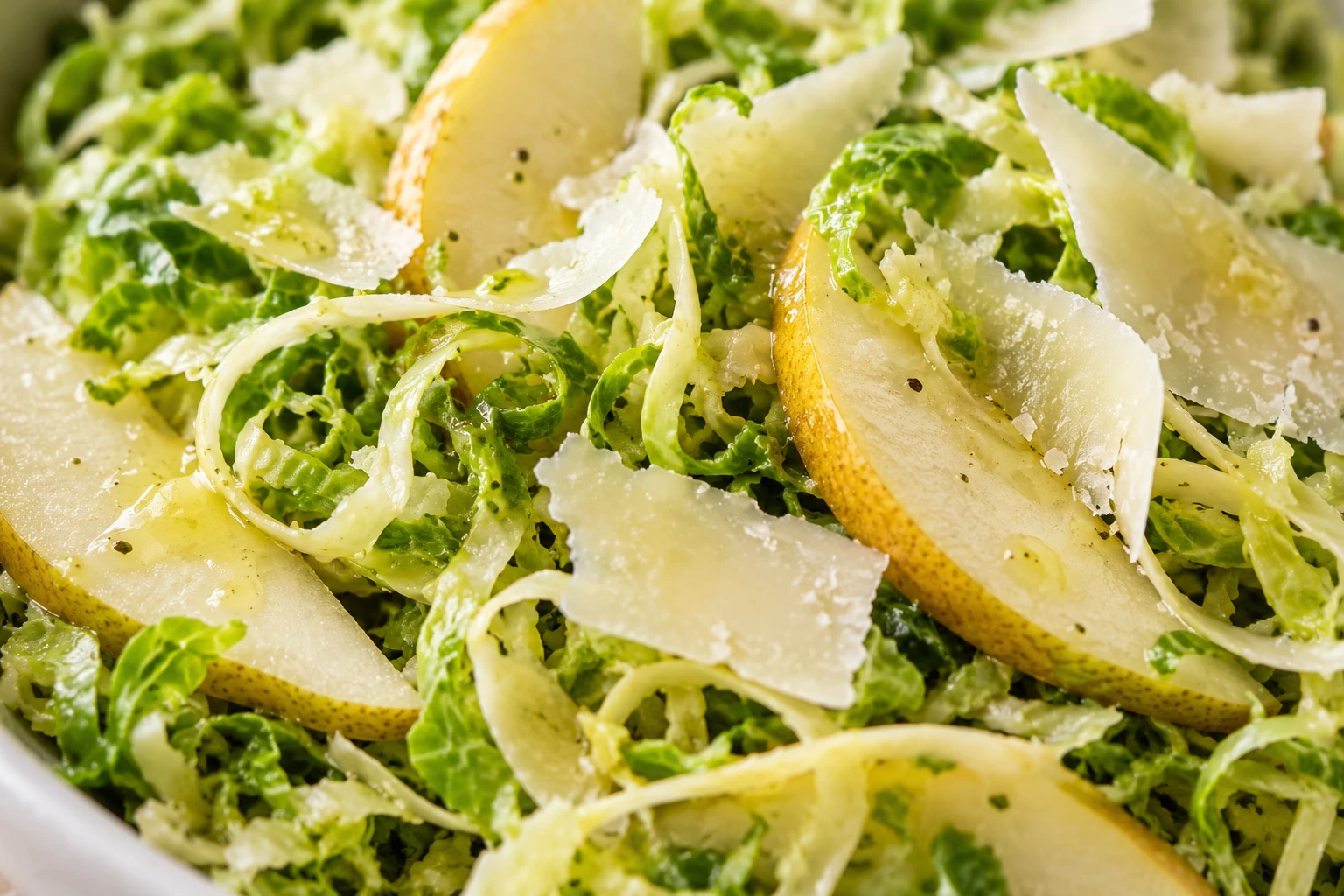 Thin Brussels sprout ribbons hold crisp pear slices and fine Parmesan curls with a light sheen.