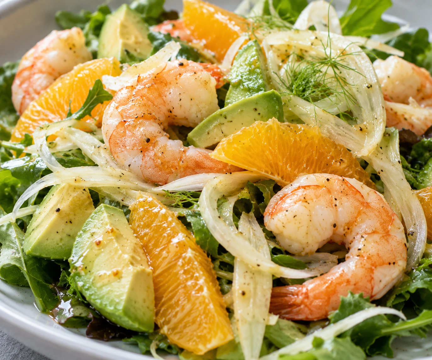 A close view shows tender shrimp, citrus segments, avocado, and delicate fennel shavings.