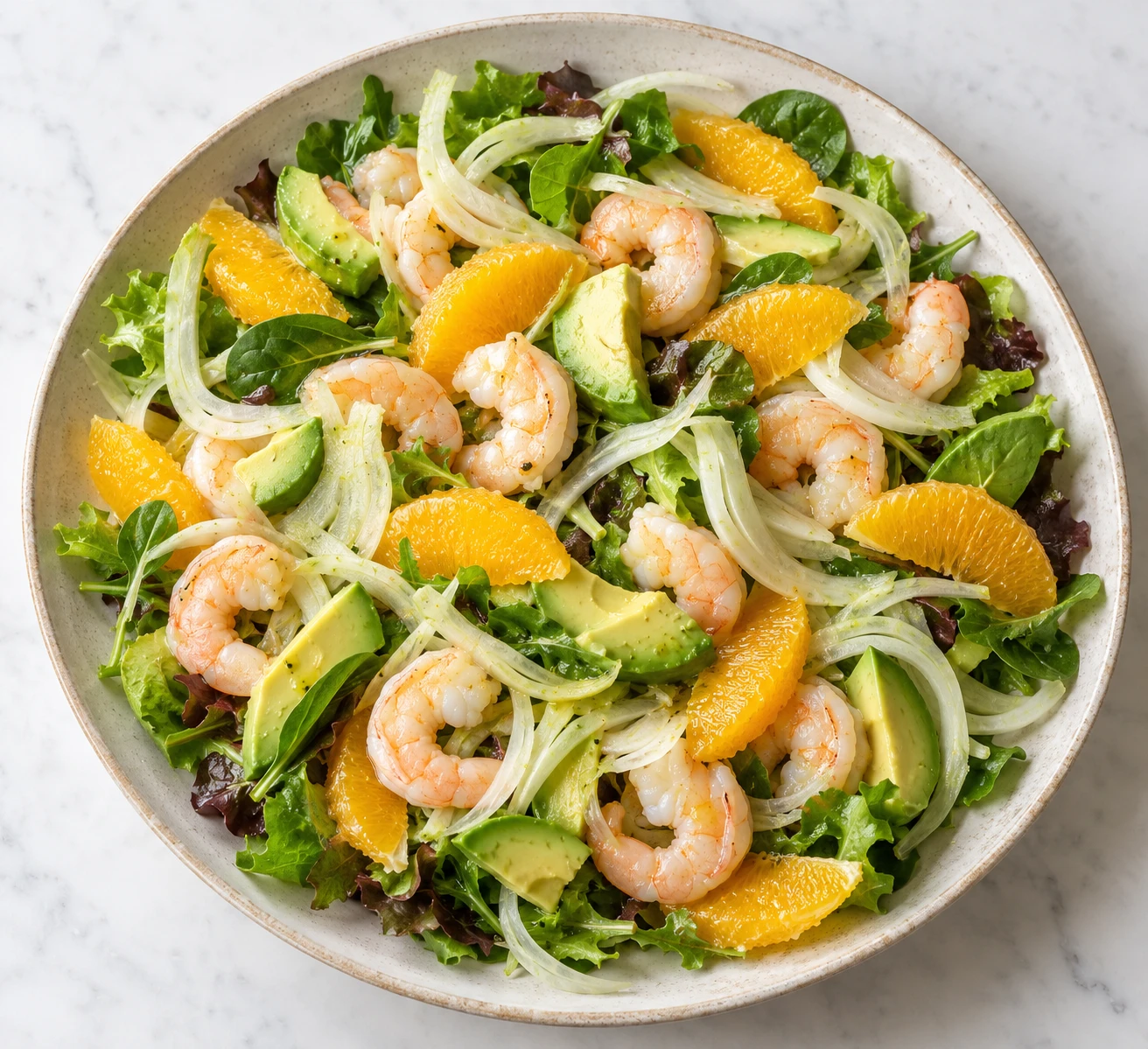 Chilled shrimp, orange, avocado, and shaved fennel cover a platter of crisp greens.