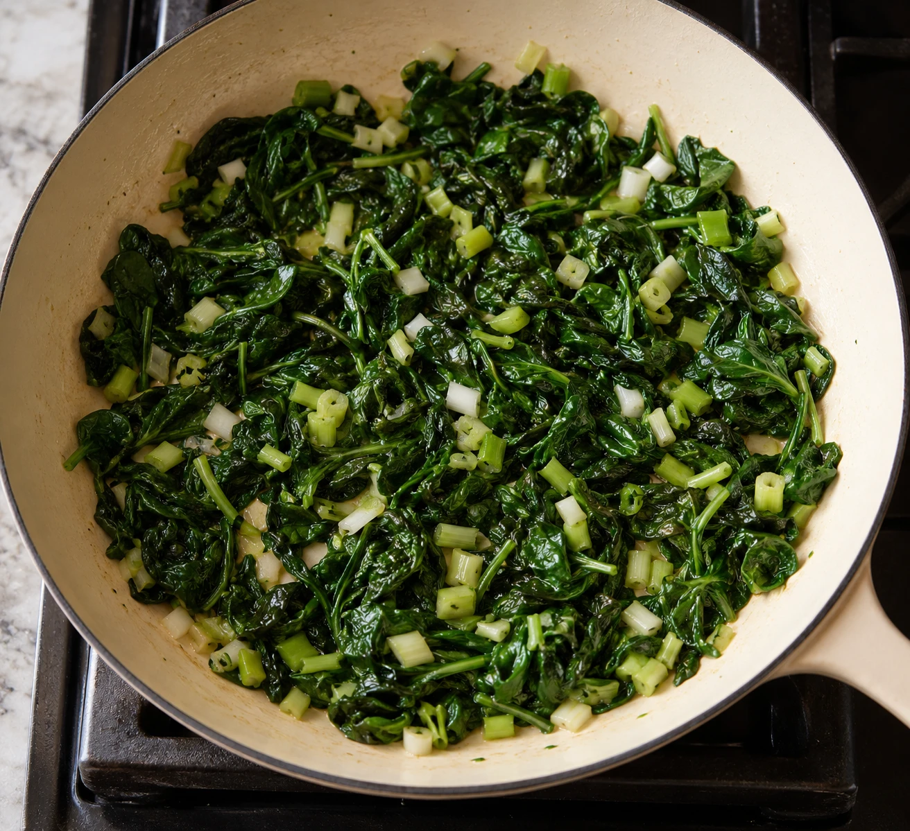 Wilted spinach and softened scallion whites cover the skillet before the egg mixture is poured in.