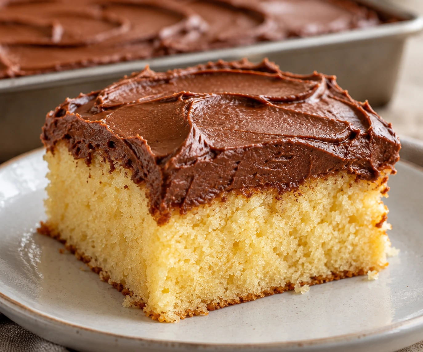 A close slice reveals tender yellow cake under a thick layer of chocolate buttercream.